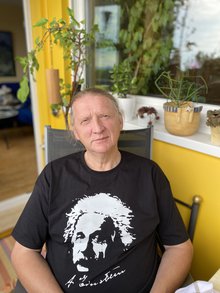 Der ehemalige langjährige Leiter des Fachbereichs Gemeinden von ver.di Hessen mit schwarzem Albert Einstein T-Shirt auf seinem Balkon in einem Gartenstuhl sitzend.