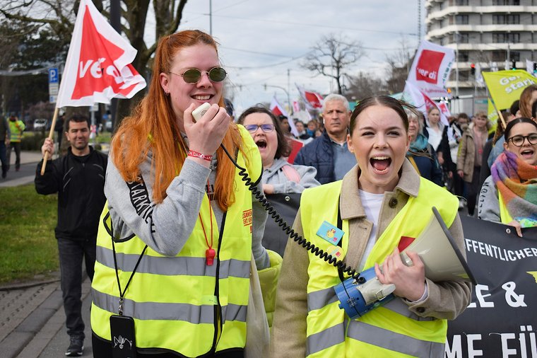 Demo, zwei Frauen halten Megaphon und rufen laut.