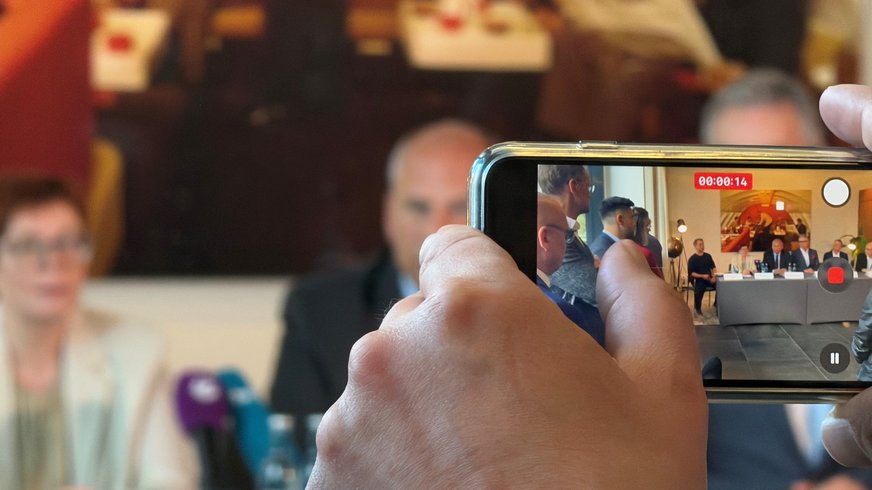 Blick von hinten durch Handy, das grade ein Foto aufnimmt.