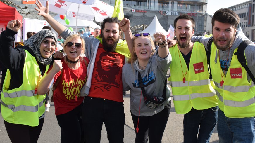 Jugendliche, die sich auf der Straße kämpferisch im Arm halten und die Fäuste recken