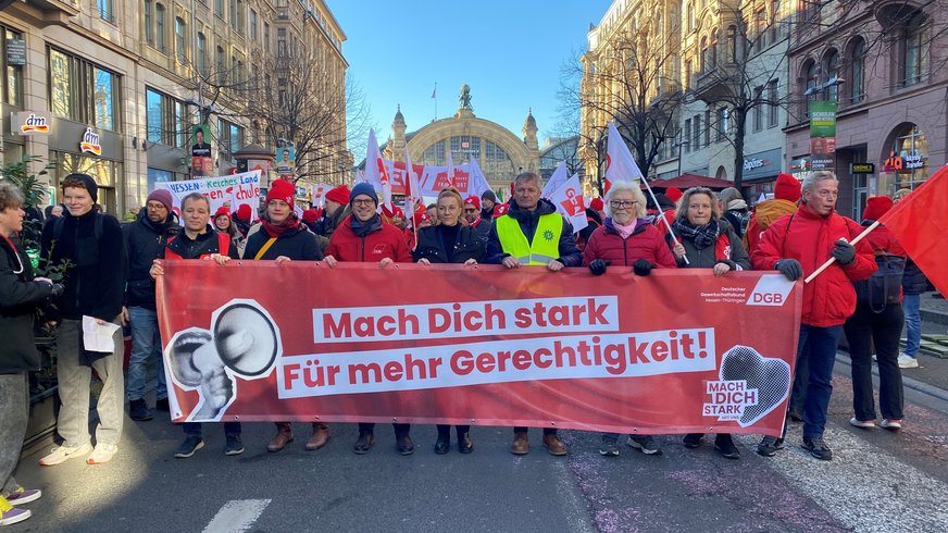 Banner "mach dich stark für Gerechtigkeit" von Leuten gehalten, im Hintergrund der Ffmer Hbf